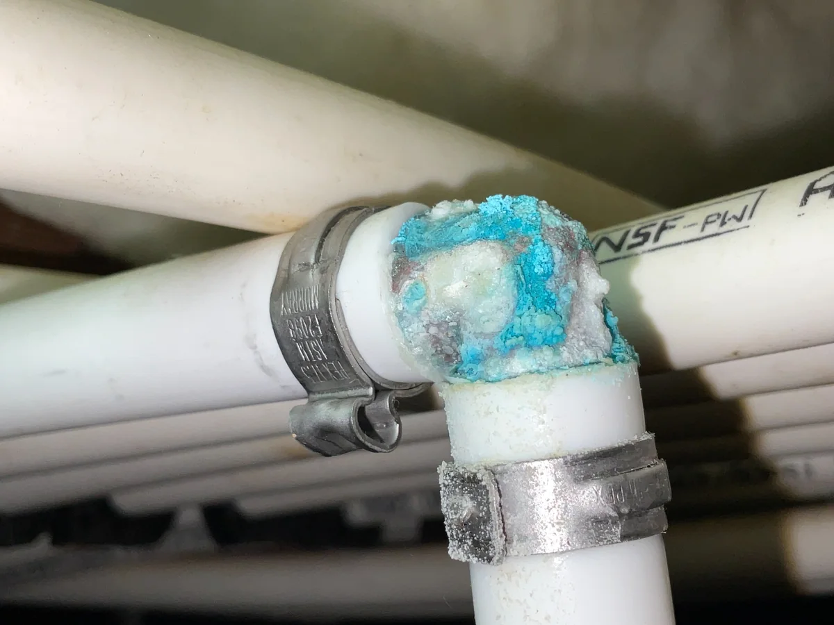 Blue-green and white corrosion deposits at a PEX plumbing fitting